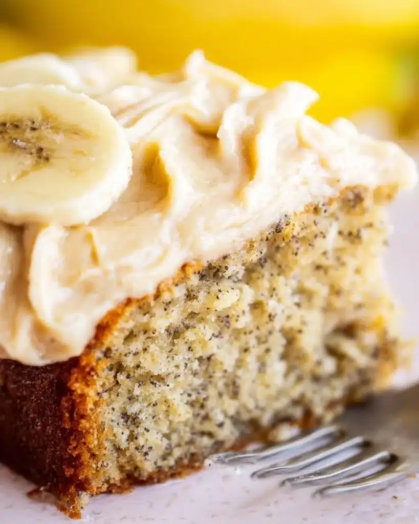 Delicious banana cake topped with spiced vanilla buttercream on a white plate.