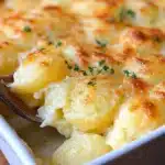 Creamy Classic Delmonico Potatoes topped with cheese in a baking dish
