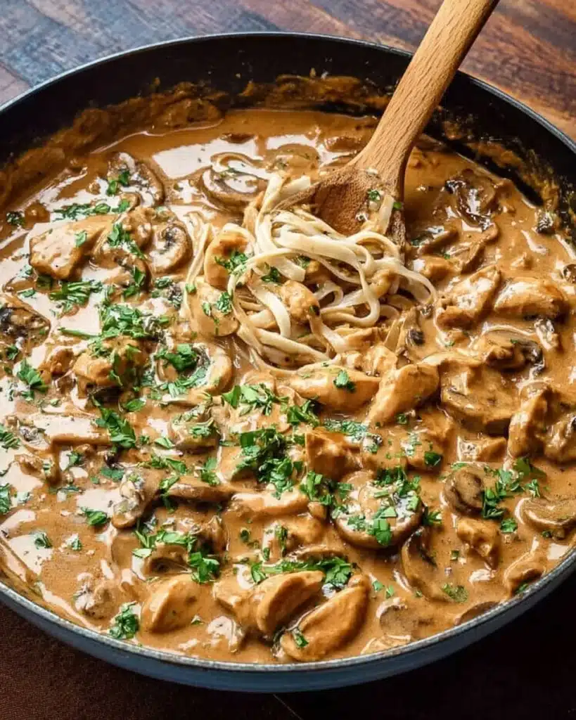 Delicious creamy Chicken Stroganoff served with pasta and garnished with herbs.