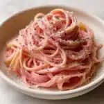 Creamy vegan pink pasta dish served in a bowl with fresh herbs