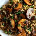 Plate of garlicky mushroom quinoa garnished with fresh herbs