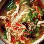 Bowl of Ginger Garlic Chicken Noodle Soup with fresh herbs and spices.