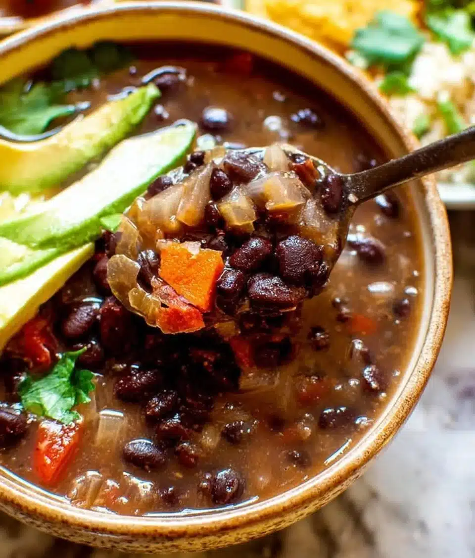 Bowl of homemade black bean soup garnished with cilantro and lime wedges