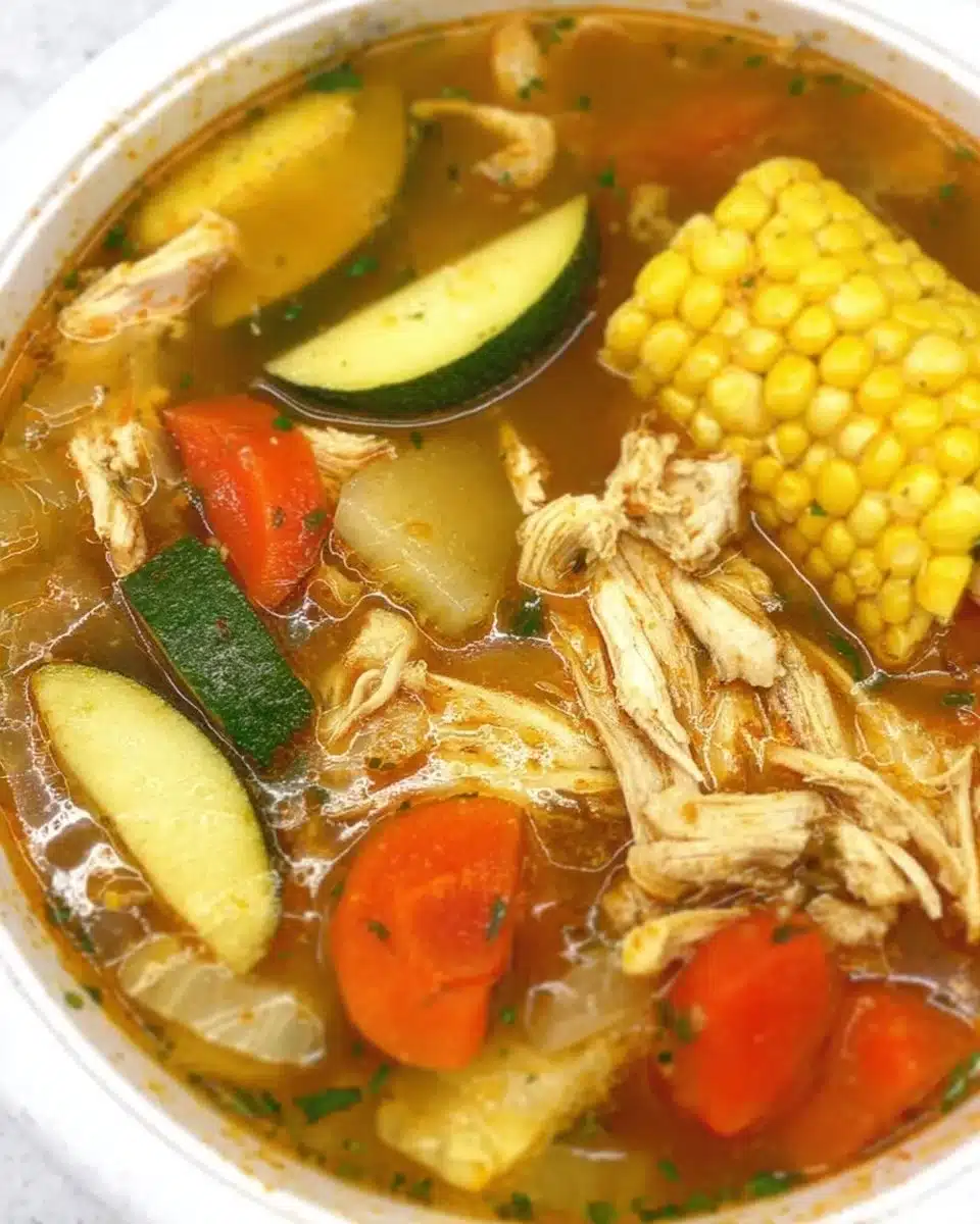 Homemade chicken broth simmering in a pot with fresh herbs and vegetables.