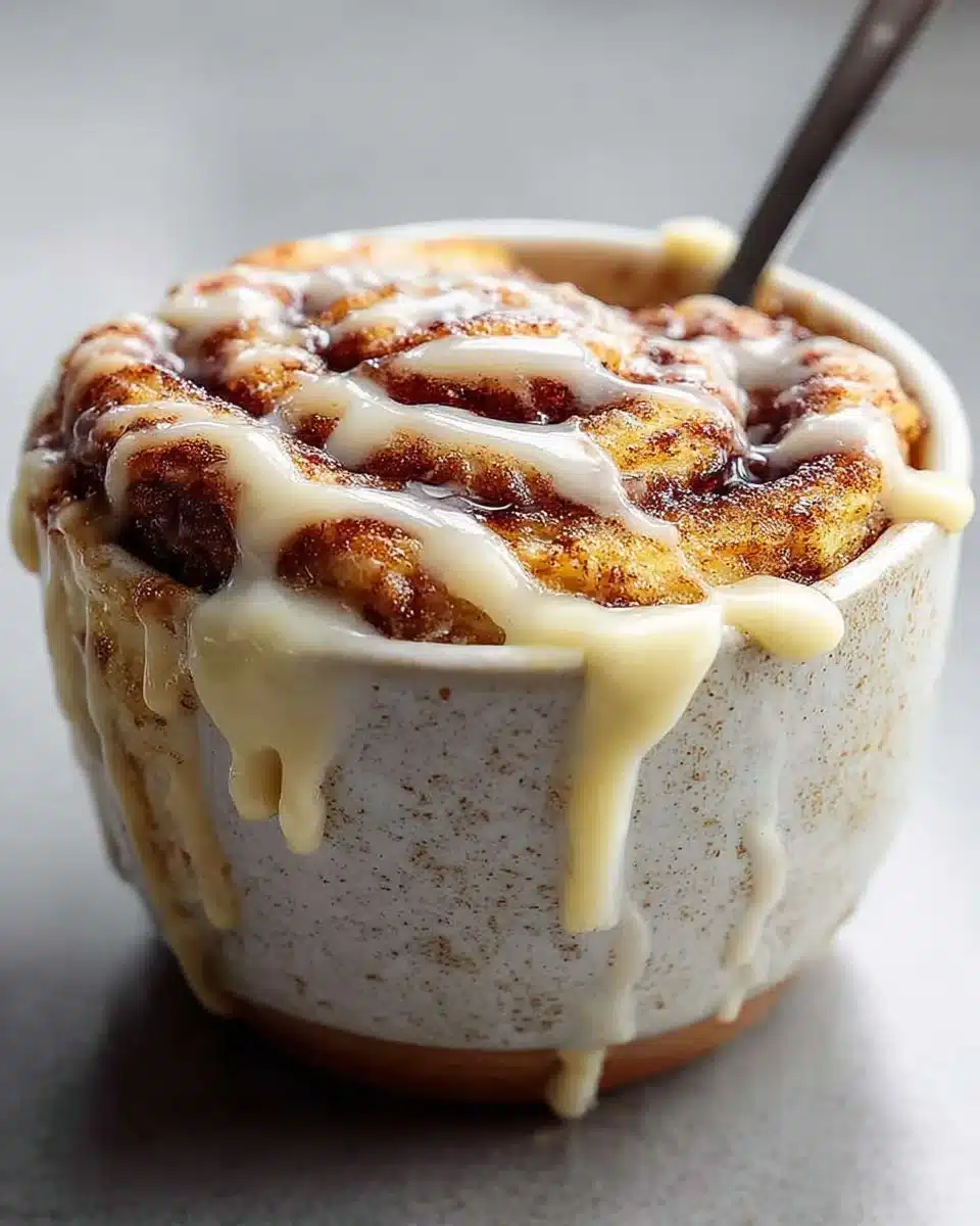 Warm Cinnamon Bun Mug Cake served in a mug with cinnamon and icing
