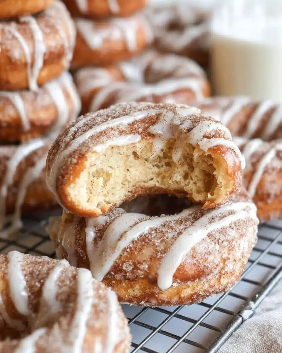 Freshly baked cinnamon roll donuts topped with icing and cinnamon