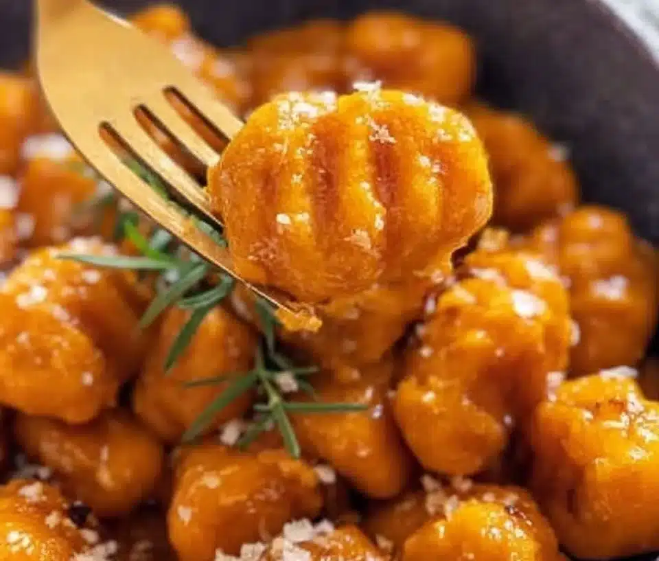 Plate of delicious homemade sweet potato gnocchi with sauce and herbs.