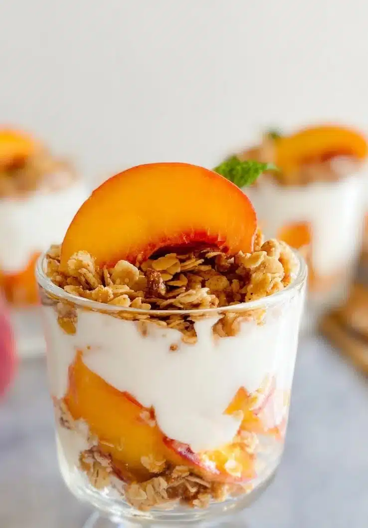 Delicious Peach Granola Parfait layered with yogurt and fresh peaches