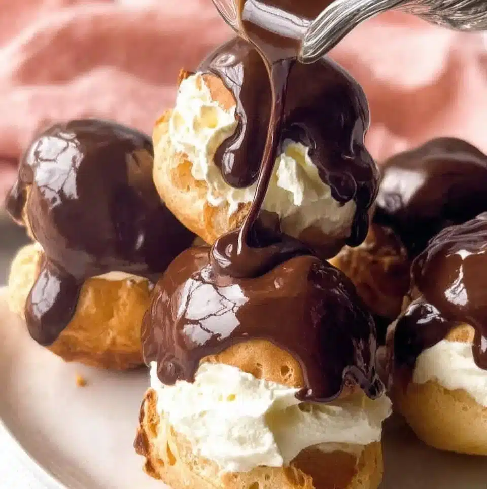 Delicious profiteroles filled with cream and drizzled with chocolate sauce