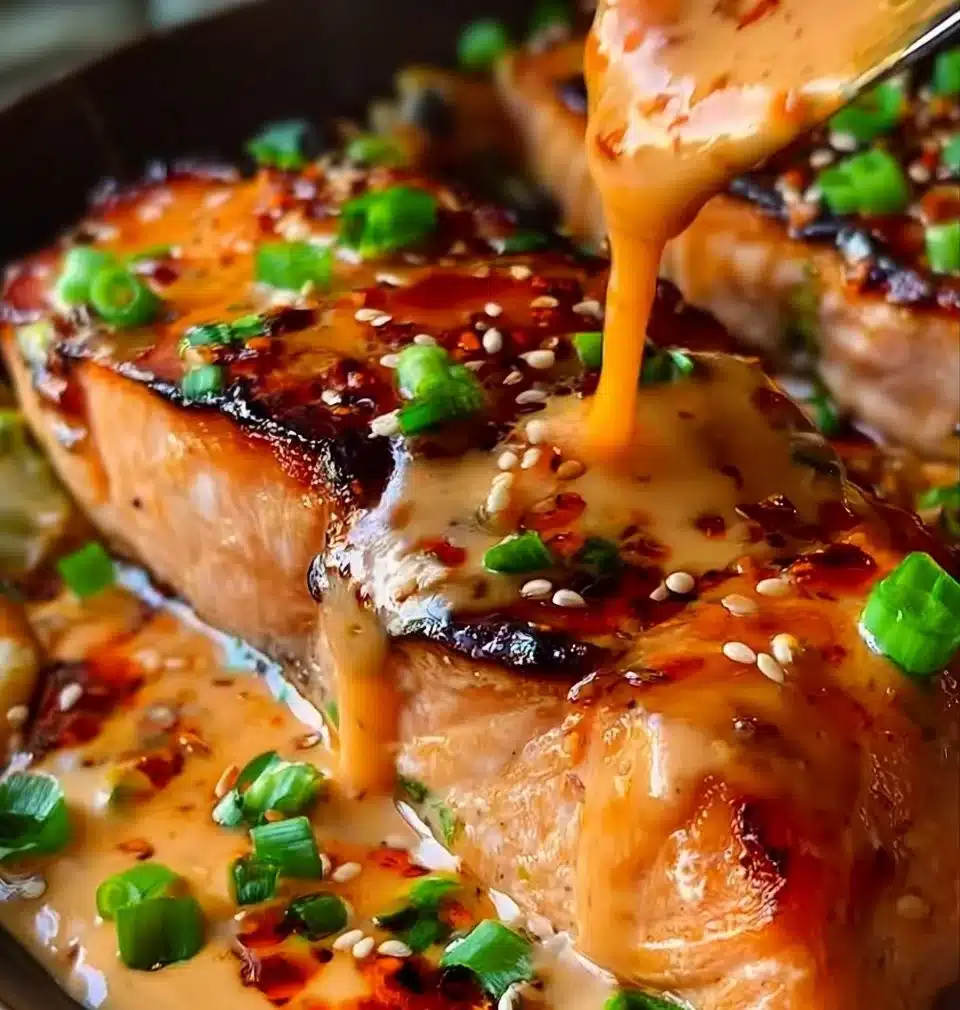 Delicious Bang Bang Salmon served with vibrant sauce and garnishes.